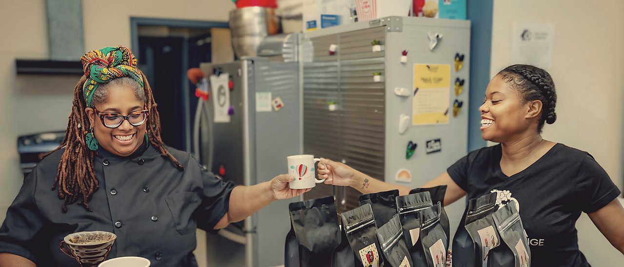 Chef Coco passing a mug of coffee at the Original Drip Dakar café